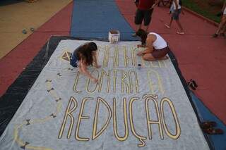 Jovens pinta faixa pedindo que não seja aprovada a redução da maioridade penal. (Foto: Fernando Antunes)