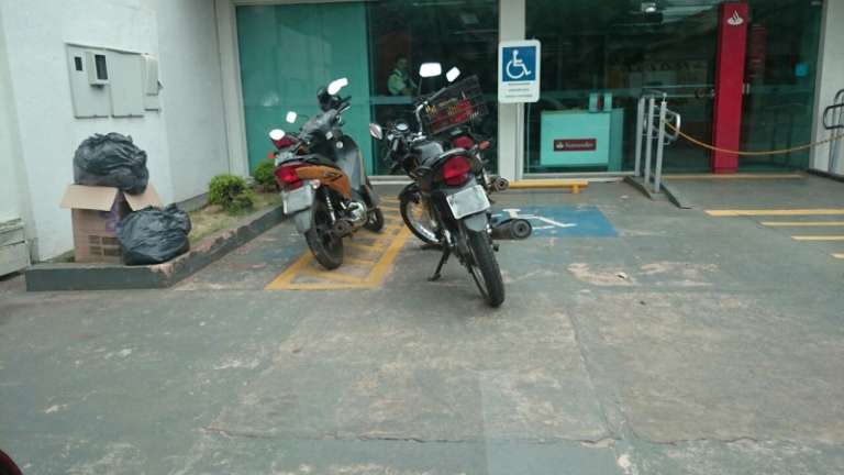 As duas motos ocupavam vaga a destinada a deficientes em agência bancária na rua Ceará.(Foto:Direto das Ruas)

