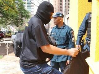 Policiais da Corregedoria com rostos cobertos com touca chegando com objetos apreendidos (Foto: Henrique Kawaminami) 