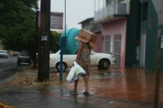 Moradora apelou para uma caixa de papelão para se proteger da chuva (Foto: Paulo Francis)