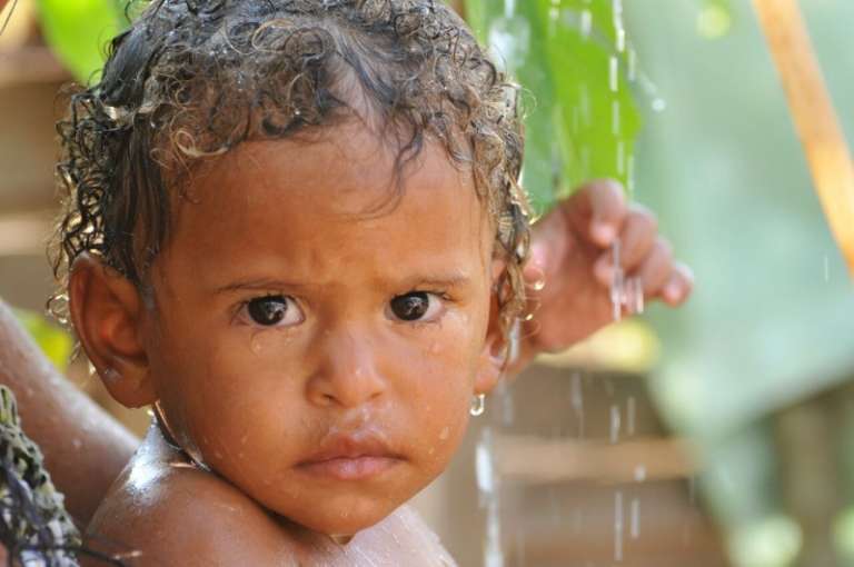 Menino se refresca em água da torneira em favela (Foto: Alcides Neto)