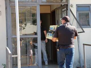 Policial entra na sede do Gaeco com material eletrônico apreendido.