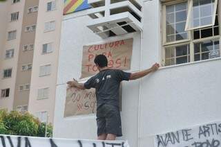 Manifestante fixa cartaz na fachada da Fundac. (Foto: Marcelo Calazans)