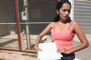 Karina mostra nota fiscal de material de construção financiado. 