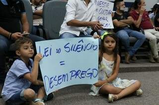 Crianças exibem cartaz contra lei do silêncio durante audiência na Câmara Municipal (Foto: Henrique Kawaminami)