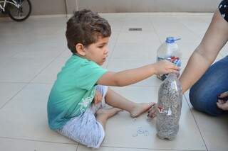 Pietro separando as tampinhas de alumínio na garrafa (Foto: Alana Portela)