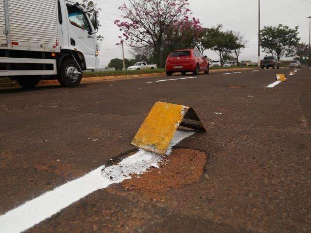 Equipe da Prefeitura gasta tinta para pintar faixa sobre buracos em avenida