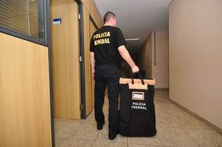 Policial federal com documentos apreendidos em empresas investigadas. (Foto: Luciano Muta)