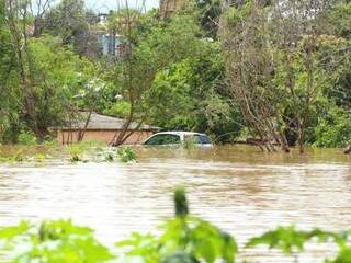 Carro (no fundo) totalmente ilhado na enchente.
(Foto: André Bittar/Arquivo).