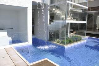 A piscina em forma de “U” é acompanhada de uma cascata que pode ser vista de dentro da casa.