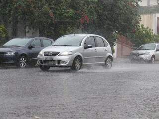 Veículo transitando na região central de Campo Grande evidencia chuva que atinge o local (Foto: Marcos Ermínio)