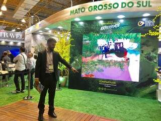 O diretor-presidente da Fundtur (Fundação de Turismo de Mato Grosso do Sul), Bruno Wendling, diante do telão da realidade aumentada na feira da Abav (Foto: Paulo Nonato de Souza)