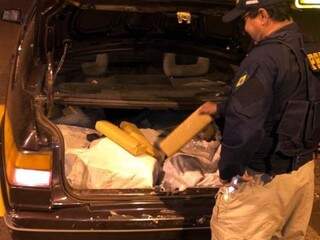Policial retira tabletes de maconha do porta-malas do carro apreendido ontem à noite (Foto: Divulgação)