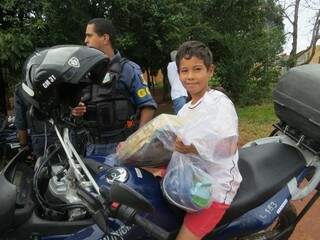 Criança moradora do Jardim Noroeste todo fez com brinquedo novo, tirando foto na viatura da Guarda Municipal. (Foto: Divulgação/GMCG)