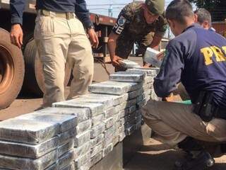Policiais rodoviários e soldados do Exército empilham tabletes de cocaína apreendidos em Sidrolândia (Foto: Divulgação/PRF)