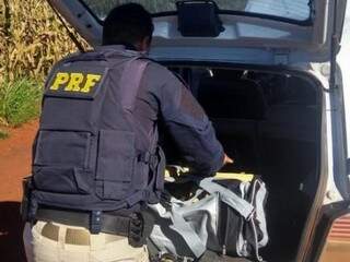 Policial vistoria malas com pasta-base de cocaína encontradas em Agile (Foto: Divulgação)