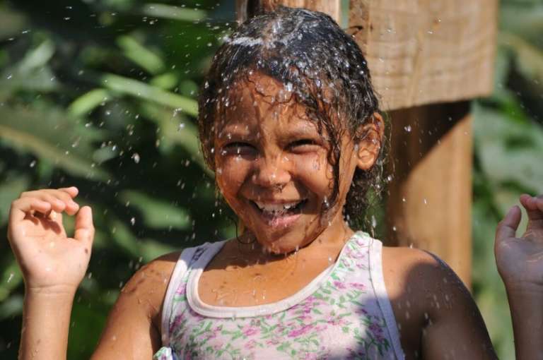 Menina festeja ao tomar banho em torneira na Favela Cidade de Deus (Foto: Alcides Neto)