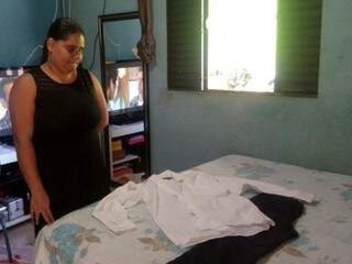 Márcia da Silva Santos Teodoro junto a roupa que providenciou para enterro do tio. (Foto: Simão Nogueira)