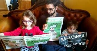 Julia, o pai André Mazini e o irmãozinho lendo Charlie Hebdo. 