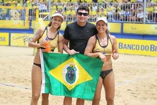 A sul-mato-grossense Talita e a capixaba Larissa posam para foto com o treinador da dupla, Reis Castro, segurando a bandeira do Ceará, onde elas treinam (Foto: Site da CBV)
