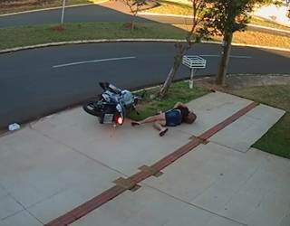 Mulher caída no chão depois que motocicleta passou reto na curva e bateu em árvore na Rua Aracruz, no Carandá Bosque III. (Foto: Reprodução vídeo enviado ao Direto das Ruas)
