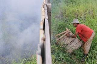 Com medo que o fogo invadisse a area em que trabalhava, Claudemiro começou tirar as madeiras próximas ao fogo. (Foto: Alcides Neto)