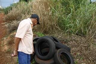 Ademar surpreso ao encontrar larvas do mosquito da dengue em pneus jogados no fundo de casa. (Foto: Cleber Gellio) 