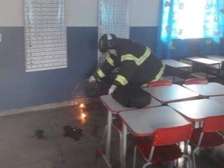 Militar apagando chamas que atingiram ventilador da sala de aula. (Foto: Corpo de Bombeiros) 