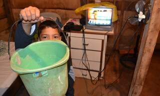 Filho da manicure Delanir mostra o balde improvisado no meio da casa. (Foto: Minamar Júnior)