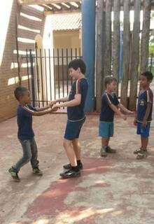 Thiago (mais alto ao centro) no pátio da escola, feliz ao brincar com o colega, o que é uma super conquista para quem tem autismo.