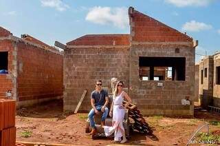 Na fachada do imóvel, casal posa com os materiais de construção.  (Foto: Juh SanNt)