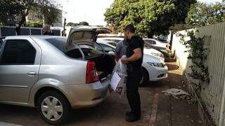 Policial chega à delegacia com documentos apreendidos em Dourados (Foto: Adilson Domingos)