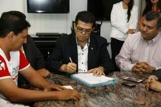 Prefeito Gilmar Olarte assinando convênio com a assinou nesta manhã convênio com a Brasil Card. (Foto: Cleber Gellio) 