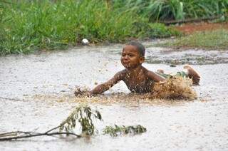 Menino brinca em água da chuva na Cidade de Deus (Foto: Alcides Neto)