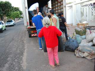 Vizinhos ajudam a colocar pertences da família em caminhão do Cetremi.