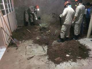 Bombeiros desenterrando o corpo nos fundos da residência. (Foto: JP News) 