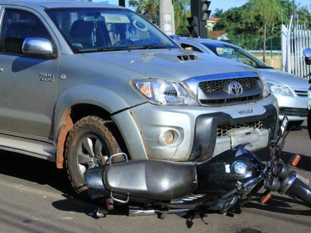 Condutora fura sinal e motociclista vai parar embaixo de caminhonete 