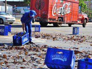 Funcionários de distribuidora retiram carga de cerveja espalhada pela pista. Garrafas viram caco. (Foto:João Garrigó)