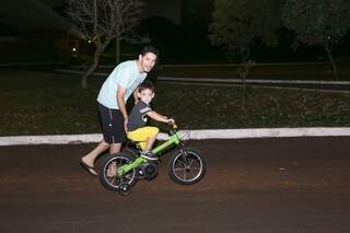 Daniel Silva ajudando o filho andar de bicicleta (Foto: Kisie Ainoã)