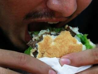 Homem &quot;se joga&quot; em um sanduíche, em hamburgueria de Campo Grande. Pesquisa de 2017 revelou que quase 70% da população de MS está com sobrepeso. (Foto: Arquivo/Alcides Neto)