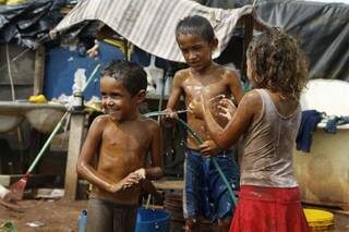 Crianças se refrescam com água em bairro carente da Capital para enfrentar o forte calor (Foto: Cleber Gellio)