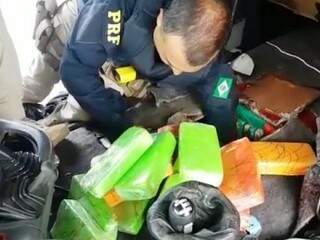 Policial retirando tabletes de pasta base de compartimento secreto (Foto: Divulgação)