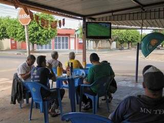 Irmãos na frente da televisão acompanham o jogo, enquanto o grupo de trás está mais interessado na cerveja e na conversa. (Foto: Saul Schramm).