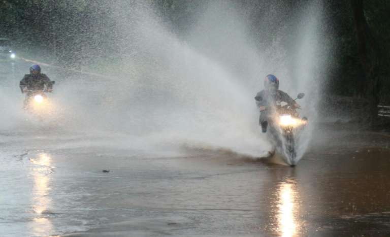 Motociclistas em via tomada pela água em Campo Grande. (Foto: Marcos Ermínio)