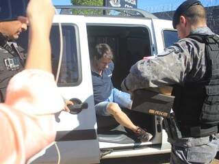Preso desce de viatura descaracterizada e policiais carregam caixas de sapato (Foto: Marina Pacheco)