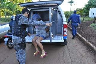 Mulher detida por suspeita de atirar em famílias sem-teto é colocada em viatura da PM (Foto: Eliel Oliveira)
