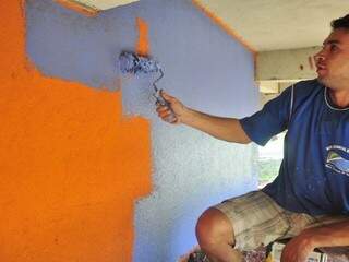 Funcionário pintando de azul parede alaranjada da Concha.