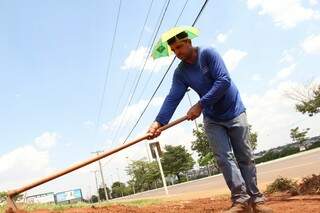 Chapéu sombrinha é estratégia para jardineiro Edivaldo se livrar do sol. (Foto: Marcos Ermínio)
