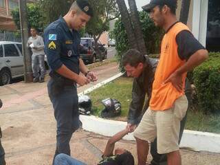 De camiseta laranja, homem que teve o iPod furtado, auxiliado por policial de folga, segurando suspeito do furto e o entregando para o policial militar (Foto: Clovis Baseggio)
