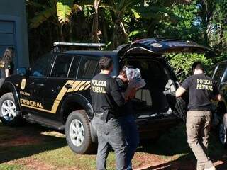 Preso em casa no Vilas Boas, homem esconde o rosto ao ser levado para viatura (Foto: Henrique Kawaminami)